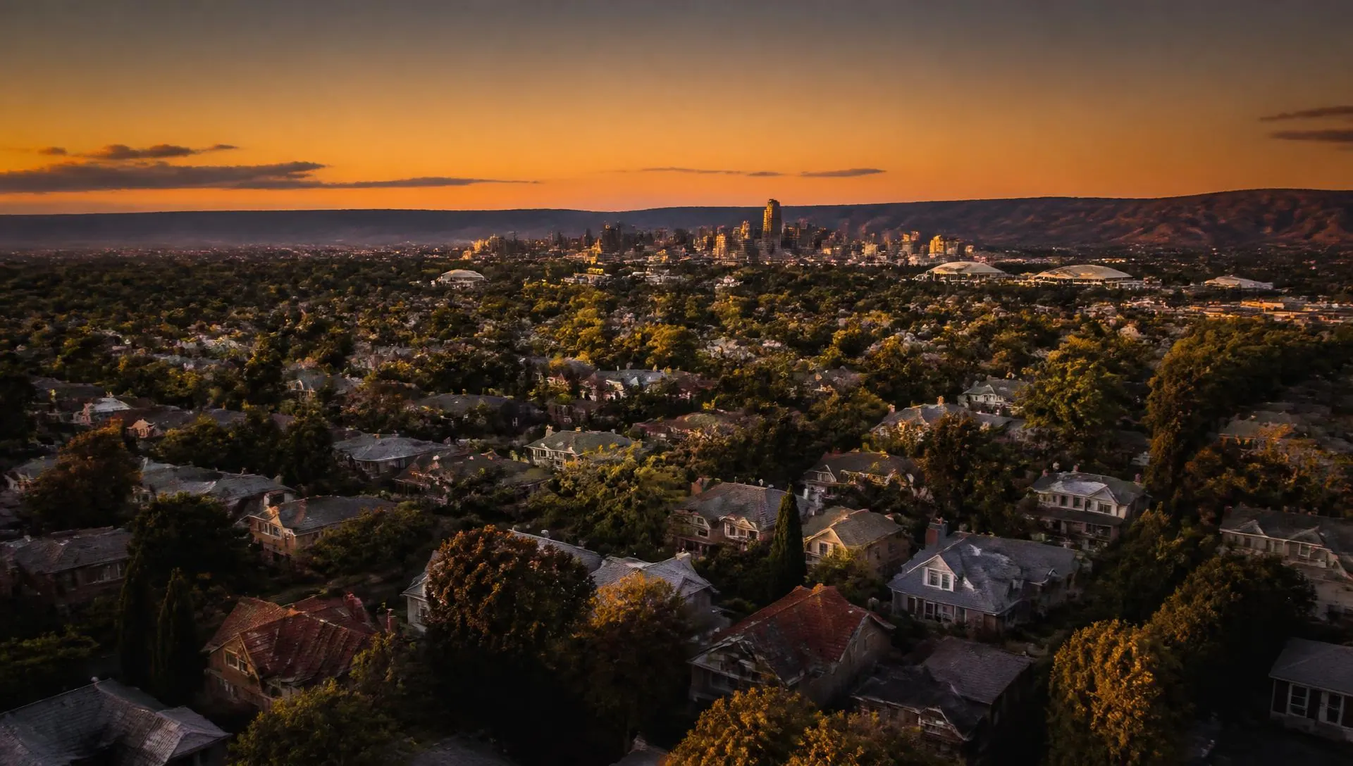 Aerial view of Adelaide suburbs at golden hour with the city skyline beyond